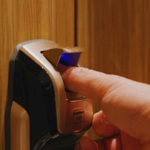 צילום ריאלי של גבר מבוגר (סביבות גיל 60+) פותח דלת בעזרת קודן טביעת אצבע